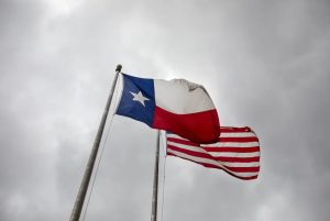The Texas governor and U.S. flags wave outside the John H. Reagan State Office Building.